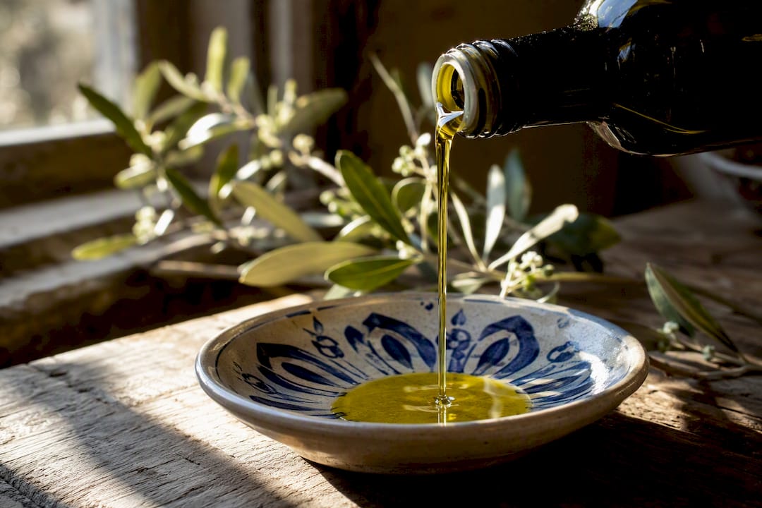 Un hilo de aceite de oliva virgen extra cayendo suavemente sobre un plato