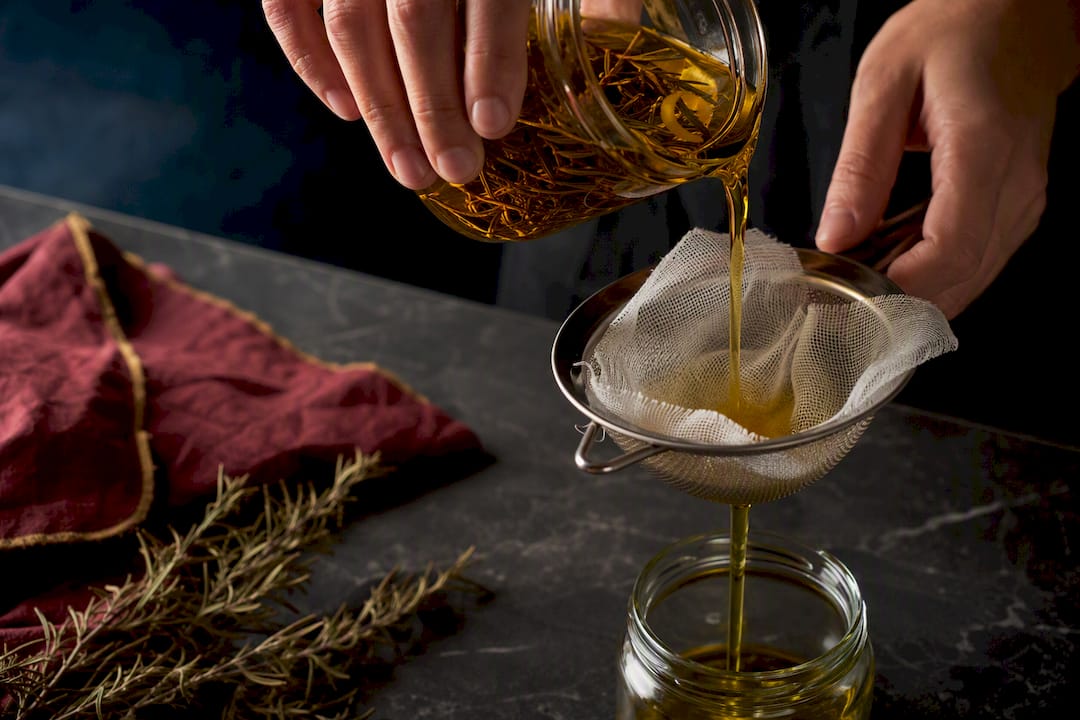 Manos colando aceite casero infusionado